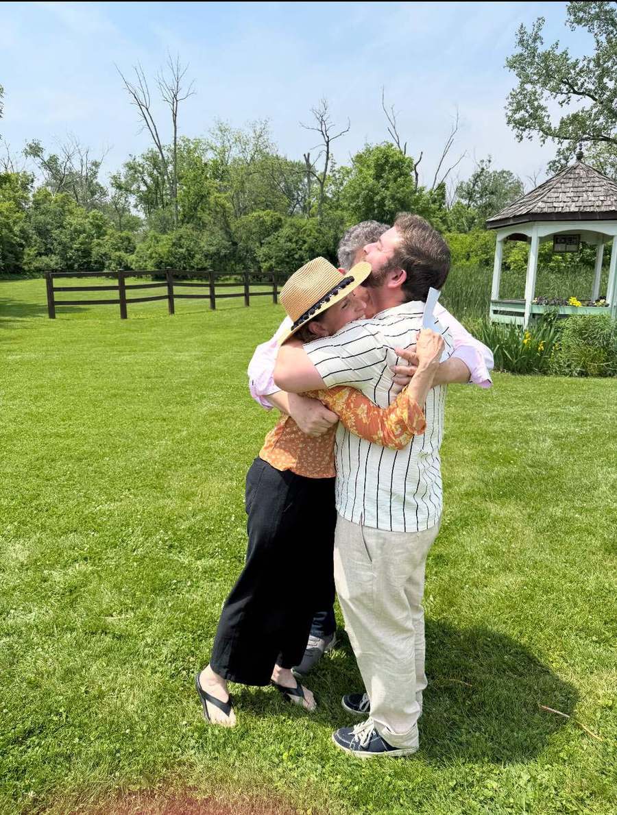 A Providence Farm resident embracing his parents on the lawn by the gazebo